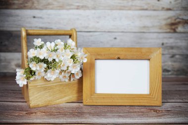 Boş fotoğraf çerçevesi ahşap arka planda çiçek buketi süslemesiyle maket yap