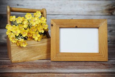 Boş fotoğraf çerçevesi ahşap arka planda çiçek buketi süslemesiyle maket yap