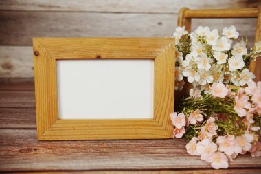 Boş fotoğraf çerçevesi ahşap arka planda çiçek buketi süslemesiyle maket yap