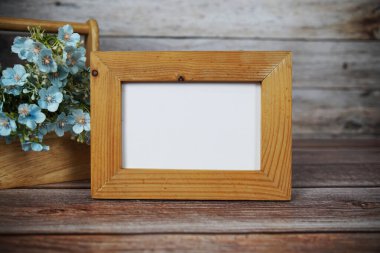 Boş fotoğraf çerçevesi ahşap arka planda çiçek buketi süslemesiyle maket yap