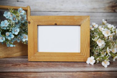 Boş fotoğraf çerçevesi ahşap arka planda çiçek buketi süslemesiyle maket yap