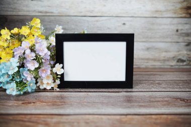 Boş fotoğraf çerçevesi ahşap arka planda çiçek buketi süslemesiyle maket yap