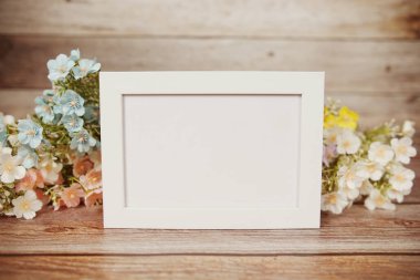 Boş fotoğraf çerçevesi ahşap arka planda çiçek buketi süslemesiyle maket yap