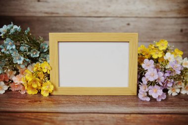 Boş fotoğraf çerçevesi ahşap arka planda çiçek buketi süslemesiyle maket yap