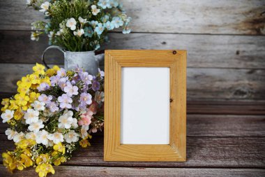 Boş fotoğraf çerçevesi ahşap arka planda çiçek buketi süslemesiyle maket yap
