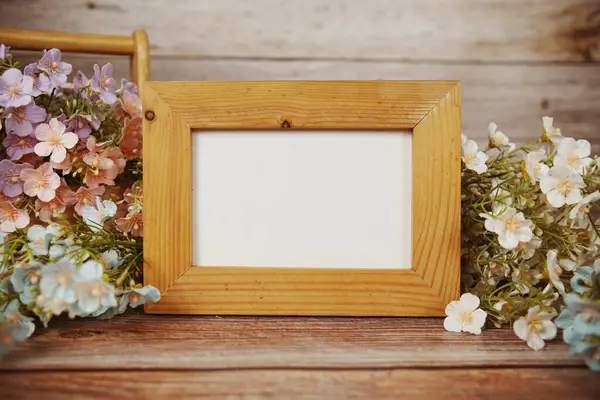Boş fotoğraf çerçevesi ahşap arka planda çiçek buketi süslemesiyle maket yap