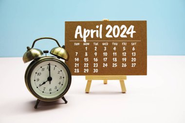 Nisan 2024 Aylık takvim sehpada ve alarm saati pastel arka planda