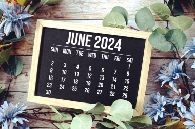 Ahşap arka planda çiçek buketi süslemesi olan Haziran 2024 aylık takvim
