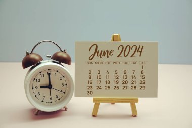 Haziran 2024 Aylık takvim sehpada ve alarm saati pastel arka planda