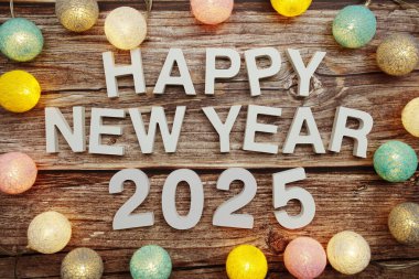 Yeni yılınız kutlu olsun 2025 alfabesi. Ahşap zemin üzerinde LED pamuk topları ile süsleyin.