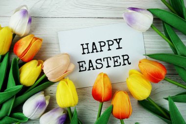 Kağıt üzerinde Lale çiçekleri ve ahşap arka planda üst görünümü olan mutlu Paskalya mesajları