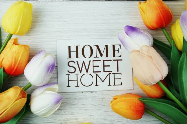 Home Sweet Home mesaj kağıdı üzerinde Lale çiçekleri buketi ile ahşap arka planda üst görünüm