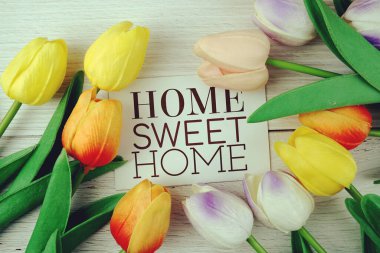 Home Sweet Home metni suni lale çiçeğiyle süslenmiş ahşap arka plan üzerine
