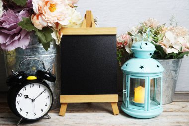 Mavi fener, çalar saat ve çiçek desenli ahşap arka planda Easel modeli.