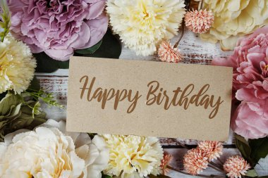 Kağıt karttaki doğum günü mesajınız kutlu olsun. Çiçek kenarlı çerçeve tahta arka planda.