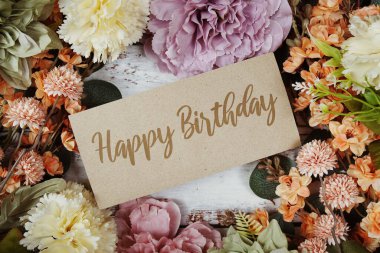 Kağıt karttaki doğum günü mesajınız kutlu olsun. Çiçek kenarlı çerçeve tahta arka planda.