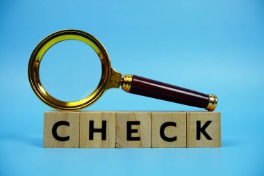 Tahta bloklar alfabe harfleri ve mavi arkaplanda büyüteçle kontrol et.