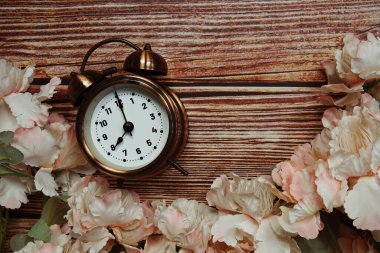 Alarm saati ve ahşap arkaplanda çiçek süslemesi olan arkaplan kopyası