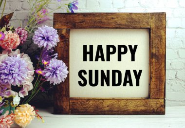 Beyaz tuğla duvar ve ahşap arka planda çiçeklerle süslenmiş mutlu Pazar metinleri