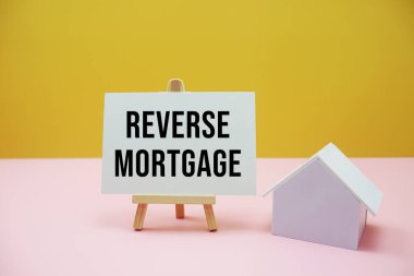 Pembe ve sarı arka plan ev modeli ile ters ipotek metni, Mali ve Mülkiyet kavramı