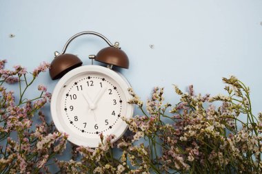 Alarm saati ve mavi arkaplanda boşluk kopyası olan çiçekler