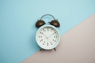 Alarm saatinin üst görünümü, mavi ve pembe zemin üzerinde uzay kopyası düz yatıyordu