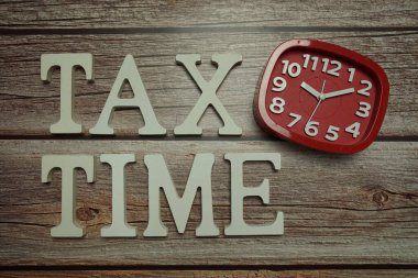 Ahşap zemin üzerinde Vergi Zamanı alfabesi ve alarm saati