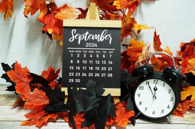 Planlama ve yönetim için ahşap arka planda akçaağaç yaprağı süslemesi bulunan Eylül 2024 aylık takvim
