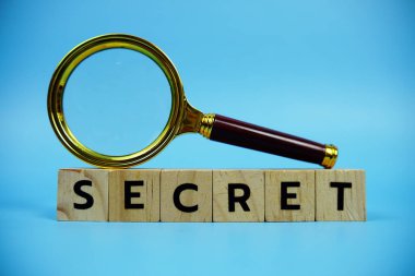 Tahta bloklar, alfabe harfleri ve mavi arka planda büyüteçle gizli.