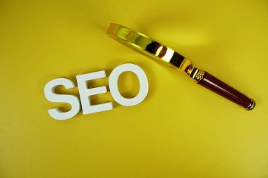 Sarı zemin üzerinde büyüteç bulunan Seo sözcükleri (Arama Motoru İyimsemesi) harfleri