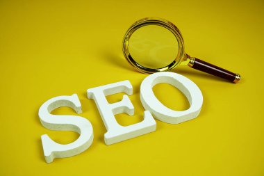 Sarı zemin üzerinde büyüteç bulunan Seo sözcükleri (Arama Motoru İyimsemesi) harfleri