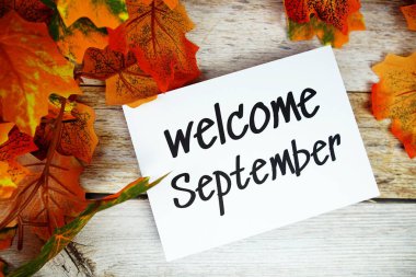 Ahşap arkaplanda akçaağaç yaprağı dekorasyonlu Eylül ayına hoş geldiniz metni