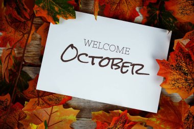 Ahşap arkaplanda akçaağaç yaprağı dekorasyonlu Ekim ayına hoş geldiniz metni