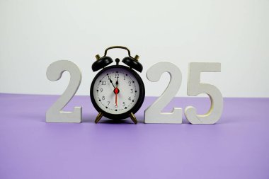 Mutlu yıllar 2025 ve mor arka plandaki çalar saat