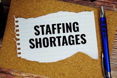 Kağıt üzerine yazılmış personel kıtlığı metni tahta arkaplanda yırtık üst görünüm