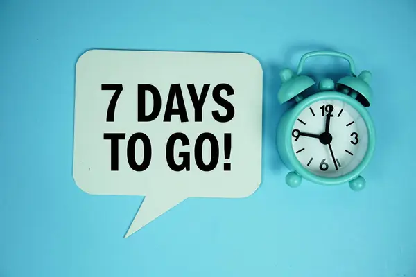 stock image 7 Days to go Days to go text on speech bluble with alarm clock top view on blue background