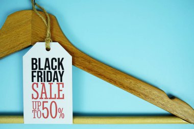 Kara Cuma indirimi% 50 'ye varan fiyat etiketi ile ahşap elbise askısı mavi arka plan, iş ve promosyon üzerinde üst görünüm