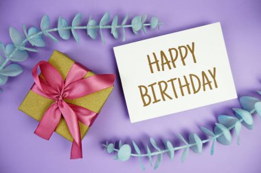 Mor zemin üzerinde hediye kutusu olan mutlu yıllar kartı.