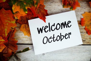 Ahşap arkaplanda akçaağaç yaprağı dekorasyonlu Ekim ayına hoş geldiniz metni