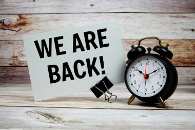 Kağıt üzerinde geri metin ve ahşap zemin üzerinde çalar saat