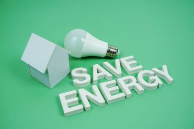 Ev modeli ve yeşil zemin üzerindeki LED ampulleri, tasarruf ve çevre dostu kavramı içeren Enerji alfabesi harflerini kaydet