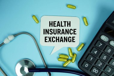 Health Insurance Exchange text with calculator, stethoscope and capsule medicine on blue background, Healthy and wellness concept clipart