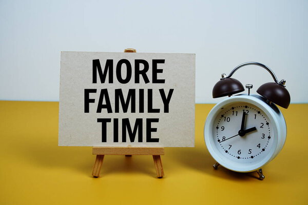 More family time quotes text on paper card and easel standing with alarm clock on yellow background