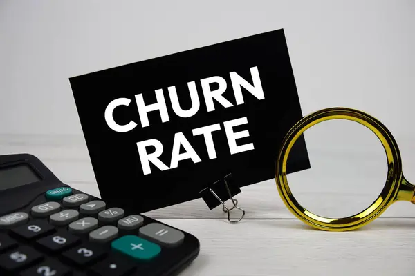 stock image Churn Rate text message with calculate and magnifying glass on wooden background