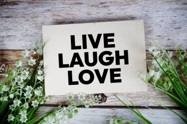 Canlı Kahkaha Aşk metni kağıt üzerinde çiçek buketi ile ahşap arka planda üst görünüm