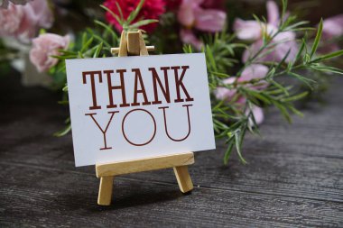 Kağıt karta tahta sehpa ve ahşap arka planda çiçek süslemesi olan bir metin yaz.