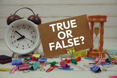 Kağıt üzerinde alarm saati ve ahşap zemin üzerinde sabit olan doğru ya da yanlış metin