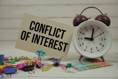 Kağıt üzerinde alarm saati ve ahşap zemin üzerinde sabit olan Çıkar çatışması metni