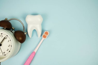 Diş fırçası ve diş fırçası ve alarm saati diş hijyeni kavramı mavi arka planda üst görünüm