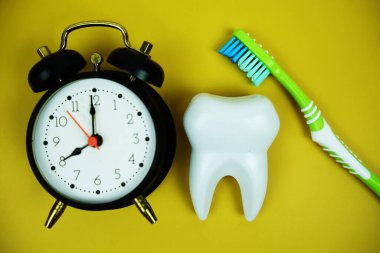 Diş fırçası ve beyaz diş fırçası modeli sarı arka planda alarm saati diş hijyeni kavramı
